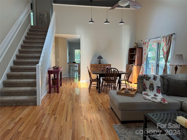 living room featuring a high ceiling, light hardwood / wood-style flooring, ceiling fan, and a healthy amount of sunlight