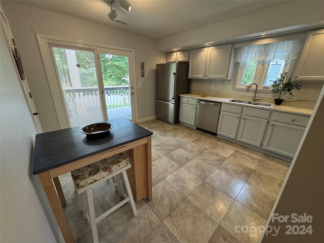 kitchen featuring sink, light tile patterned floors, appliances with stainless steel finishes, and a wealth of natural light