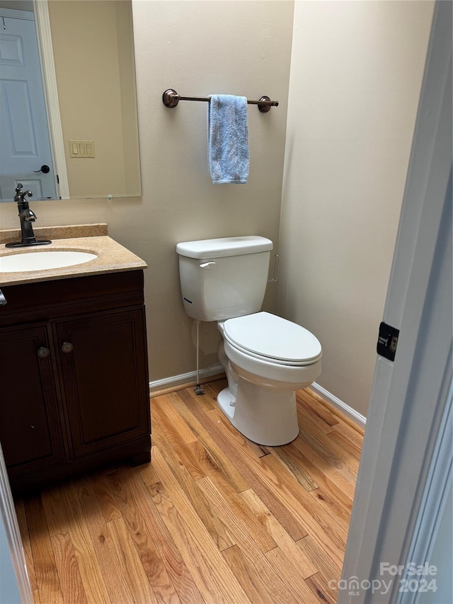 bathroom featuring hardwood / wood-style flooring, toilet, and vanity