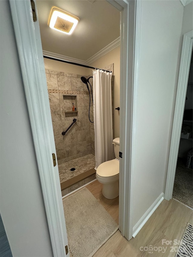 bathroom featuring toilet, ornamental molding, and curtained shower