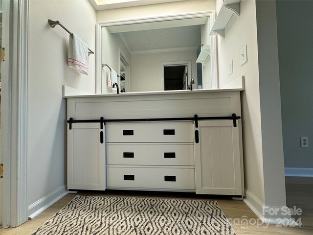 bathroom with hardwood / wood-style flooring, vanity, and ornamental molding