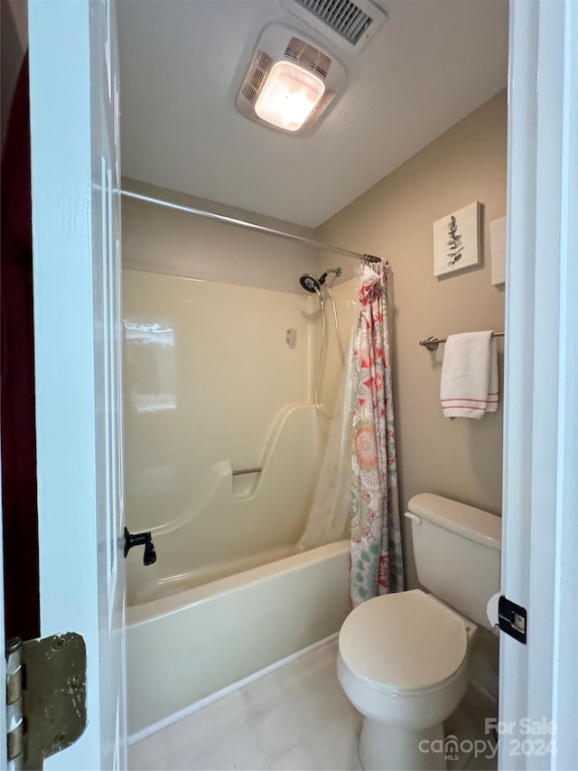 bathroom with tile patterned floors, shower / bath combo with shower curtain, and toilet