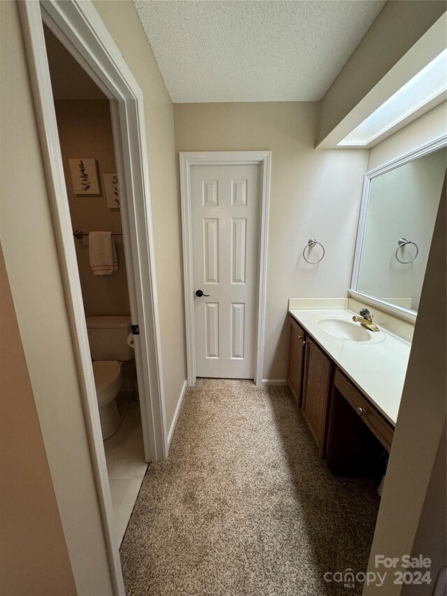 bathroom featuring a textured ceiling, toilet, and vanity