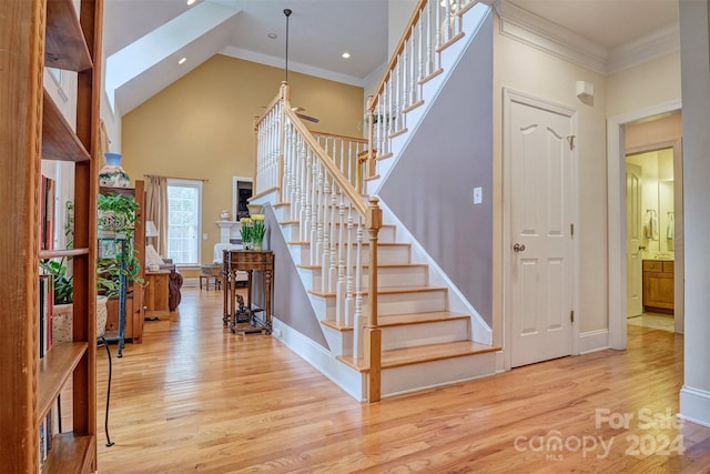 stairs with crown molding, high vaulted ceiling, and hardwood / wood-style floors