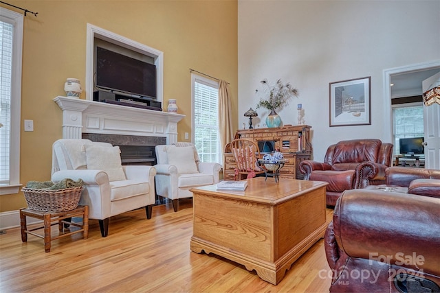 living room featuring a high ceiling, a high end fireplace, and light wood-type flooring