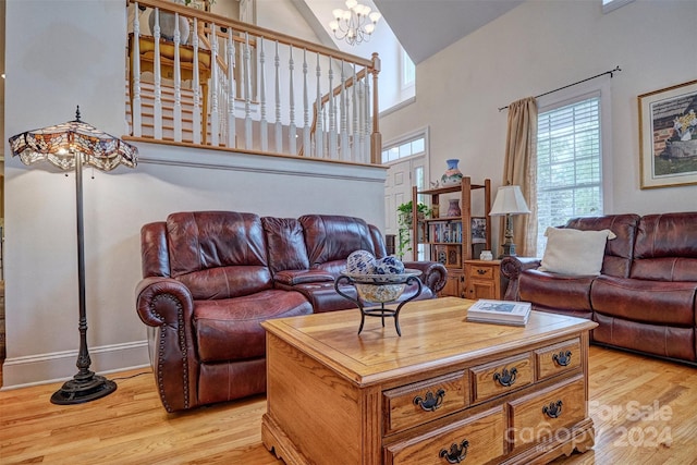 living room featuring a high ceiling, light hardwood / wood-style flooring, and a notable chandelier