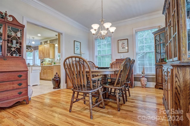 dining space featuring crown molding, light wood-type flooring, a wealth of natural light, and an inviting chandelier