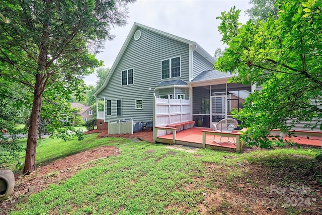 rear view of property with a sunroom, a deck, and a lawn