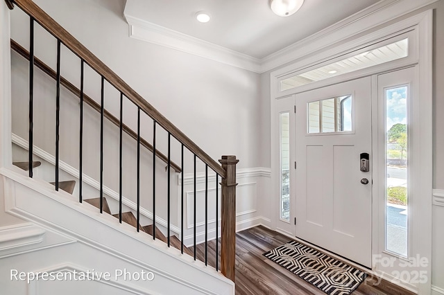 entrance foyer with ornamental molding and dark hardwood / wood-style floors