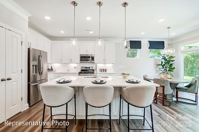 kitchen with hanging light fixtures, white cabinets, and appliances with stainless steel finishes