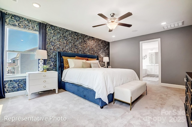 carpeted bedroom with ensuite bath and ceiling fan