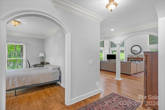 bedroom featuring decorative columns, ornamental molding, and light hardwood / wood-style flooring