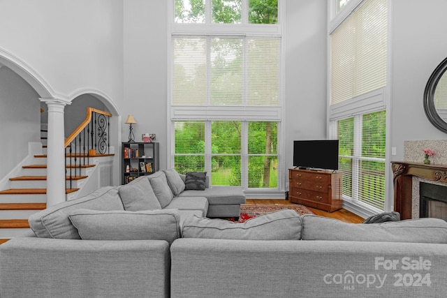 living room with hardwood / wood-style floors, a towering ceiling, a wealth of natural light, and ornate columns