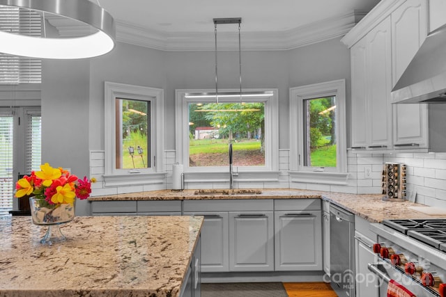 kitchen featuring decorative light fixtures, sink, decorative backsplash, ornamental molding, and wall chimney range hood