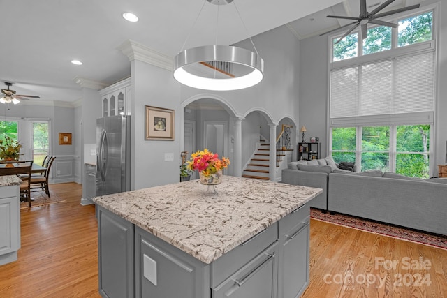 kitchen featuring gray cabinetry, ornamental molding, ceiling fan, stainless steel fridge with ice dispenser, and light hardwood / wood-style flooring