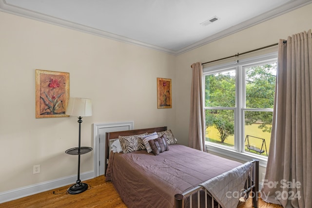 bedroom with ornamental molding and wood-type flooring