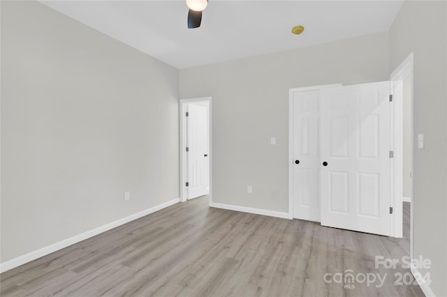 unfurnished bedroom featuring a closet, wood finished floors, a ceiling fan, and baseboards