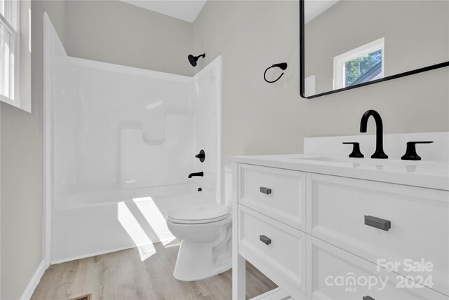 full bathroom with hardwood / wood-style floors, bathing tub / shower combination, toilet, and vanity