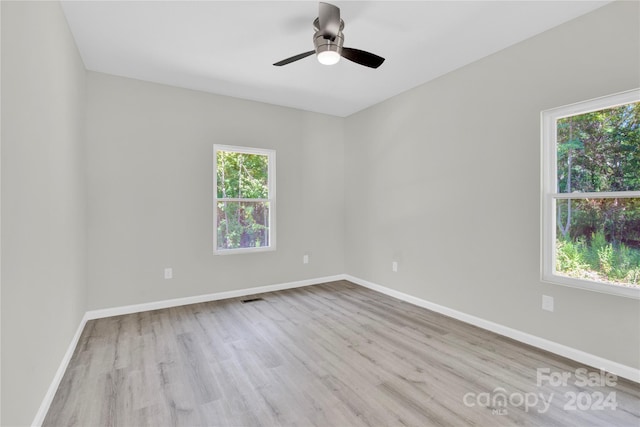 spare room featuring ceiling fan, light hardwood / wood-style flooring, and a healthy amount of sunlight