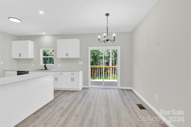 kitchen with white cabinets, baseboards, light countertops, and a sink