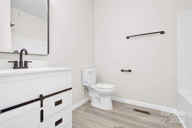 bathroom with toilet, wood finished floors, visible vents, vanity, and baseboards