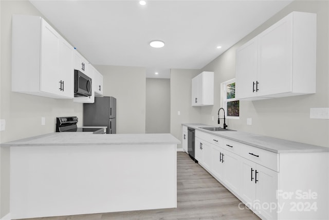 kitchen with light wood finished floors, a peninsula, stainless steel appliances, light countertops, and a sink