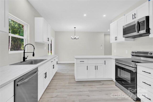 kitchen featuring light hardwood / wood-style floors, appliances with stainless steel finishes, sink, and white cabinetry