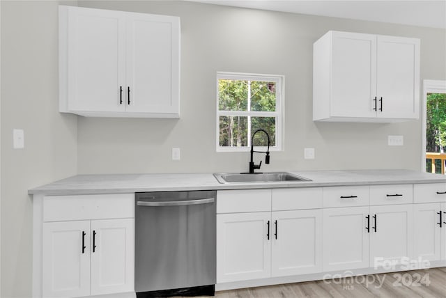 kitchen with stainless steel dishwasher, light hardwood / wood-style flooring, white cabinetry, light stone counters, and sink