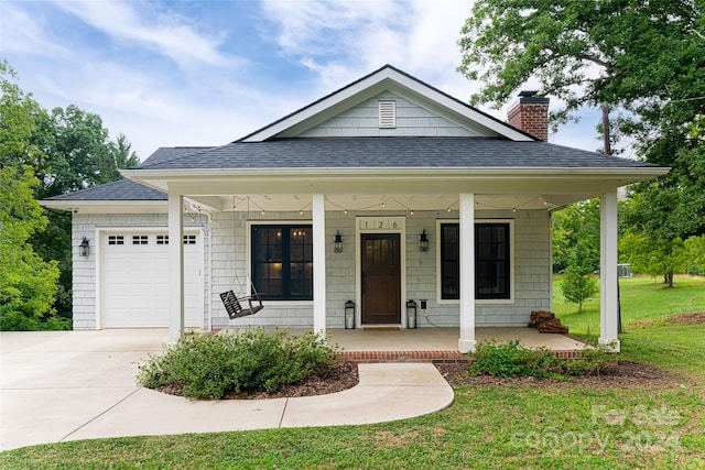 view of front of home with covered porch, a front yard, and a garage