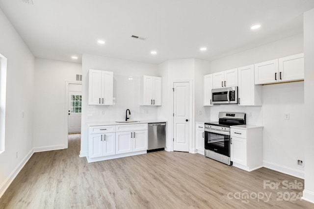 kitchen featuring white cabinets, stainless steel appliances, and light wood-type flooring