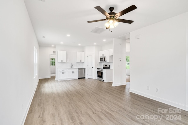 unfurnished living room featuring sink, ceiling fan, and light wood-type flooring