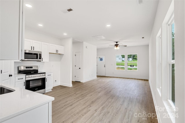 kitchen with white cabinetry, light hardwood / wood-style flooring, appliances with stainless steel finishes, and ceiling fan