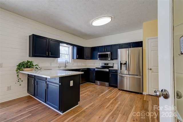 kitchen featuring stainless steel appliances, blue cabinetry, light hardwood / wood-style flooring, and kitchen peninsula