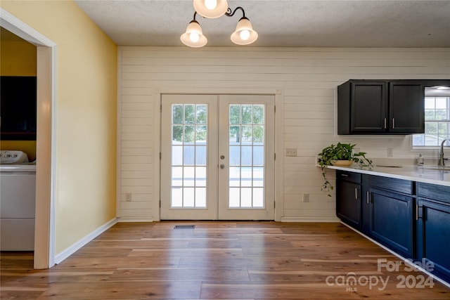 doorway featuring french doors, washer / dryer, sink, a textured ceiling, and light hardwood / wood-style floors