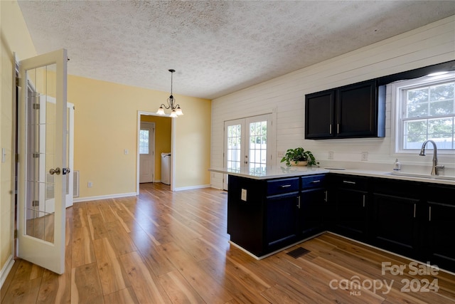 kitchen with pendant lighting, sink, light hardwood / wood-style floors, kitchen peninsula, and french doors