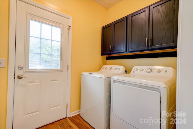 clothes washing area with washer and dryer, light hardwood / wood-style floors, and cabinets