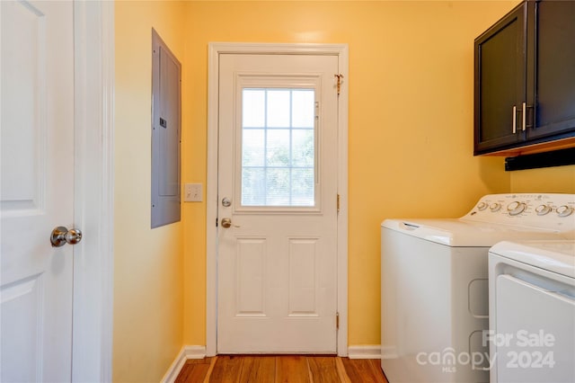 washroom featuring cabinets, electric panel, washer and clothes dryer, and light hardwood / wood-style floors