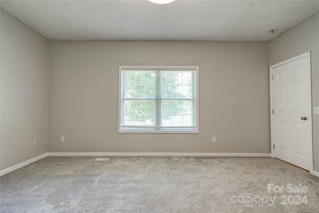 carpeted empty room featuring a textured ceiling