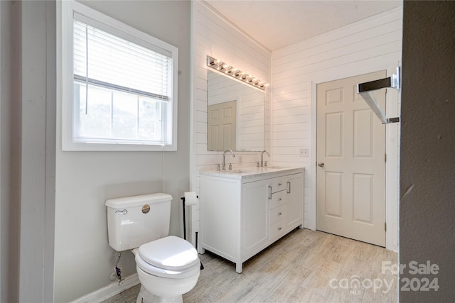 bathroom featuring wooden walls, vanity, toilet, and hardwood / wood-style floors