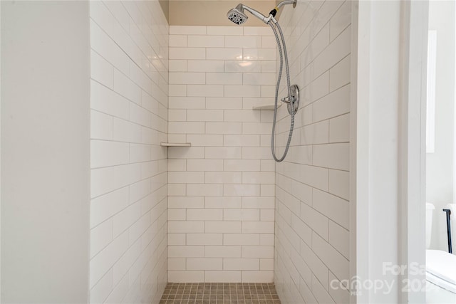 bathroom with tiled shower and toilet