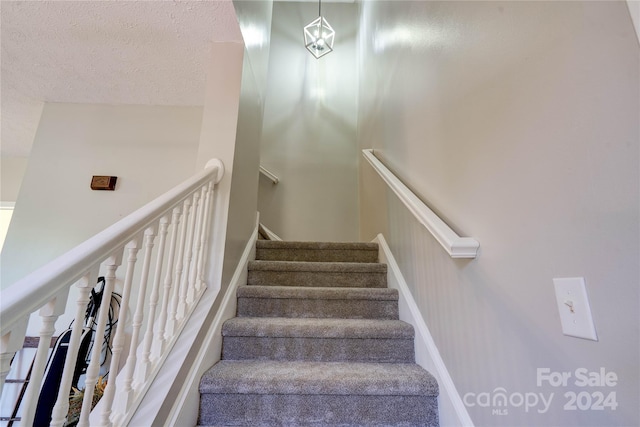 stairs with a towering ceiling and a textured ceiling