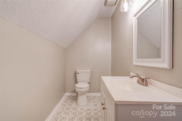 bathroom featuring lofted ceiling, vanity, toilet, and a textured ceiling