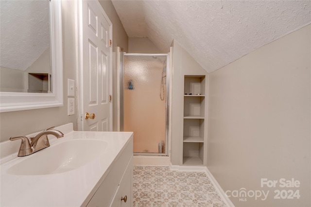 bathroom featuring walk in shower, vanity, vaulted ceiling, and a textured ceiling