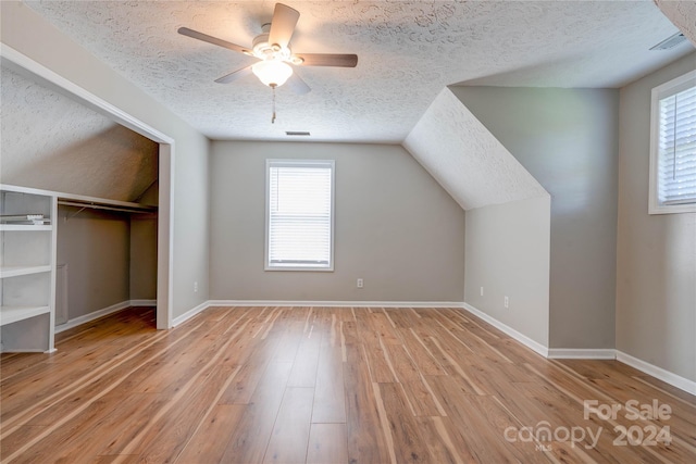 bonus room with ceiling fan, a healthy amount of sunlight, light hardwood / wood-style flooring, and a textured ceiling