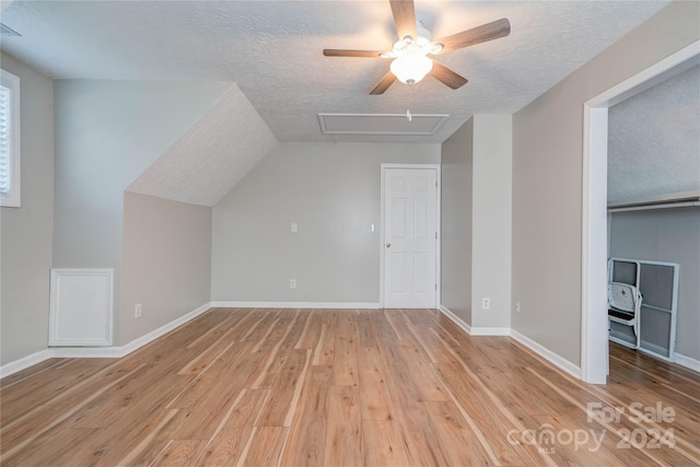 bonus room with lofted ceiling, light hardwood / wood-style flooring, and a textured ceiling