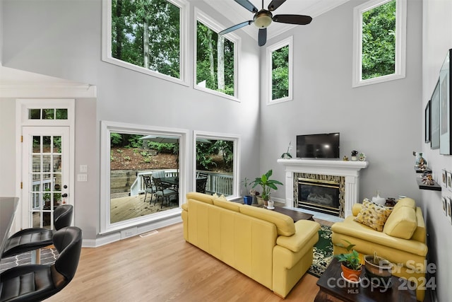 living room with light hardwood / wood-style floors, a healthy amount of sunlight, ceiling fan, and a towering ceiling