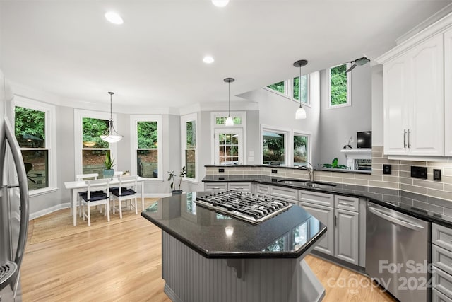 kitchen with light wood-type flooring, dark stone counters, stainless steel appliances, and tasteful backsplash