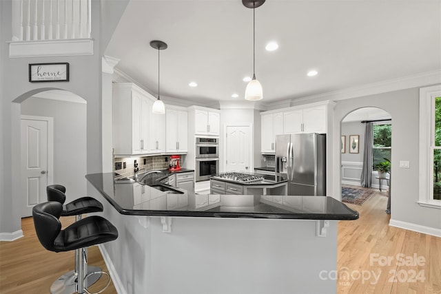 kitchen with appliances with stainless steel finishes, sink, kitchen peninsula, light hardwood / wood-style floors, and backsplash