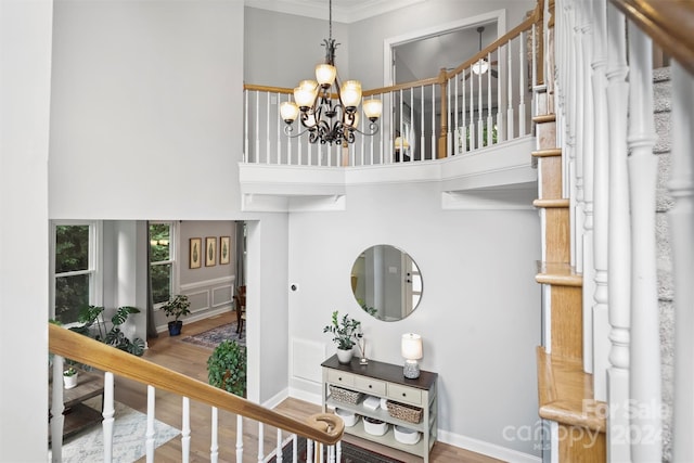 interior space with a notable chandelier, ornamental molding, wood-type flooring, and a towering ceiling