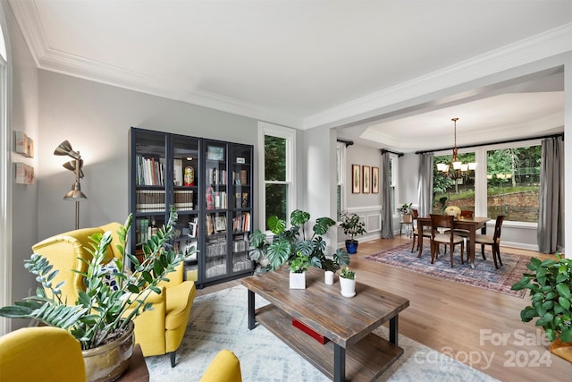 living room with crown molding, a chandelier, and light hardwood / wood-style flooring